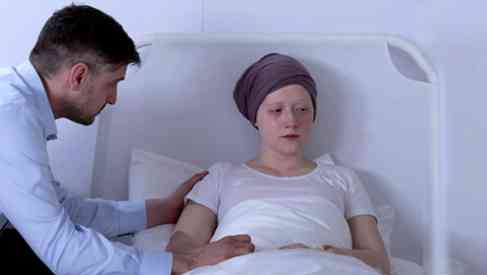 man conforting wife in hospital bed undergoing chemotherapy